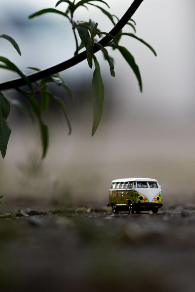 Miniature Decorative Bus on Textured Surface with Green Leaves Wallpaper