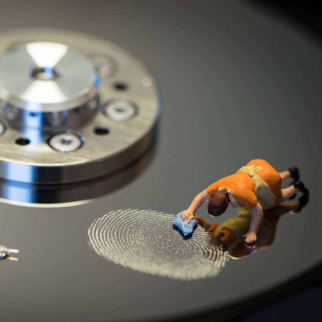Macro photo of toy maid cleaning fingerprint from reflective computer hard drive platter surface Wallpaper