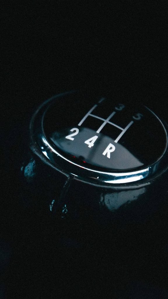 Close-up of sleek manual car gear shift knob with classic pattern on dark moody wallpaper background