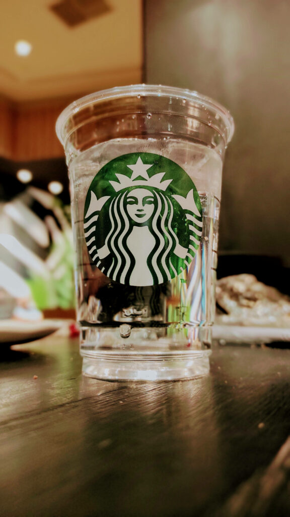Clear Starbucks cup of water on dark tabletop minimal fresh iPhone wallpaper background design