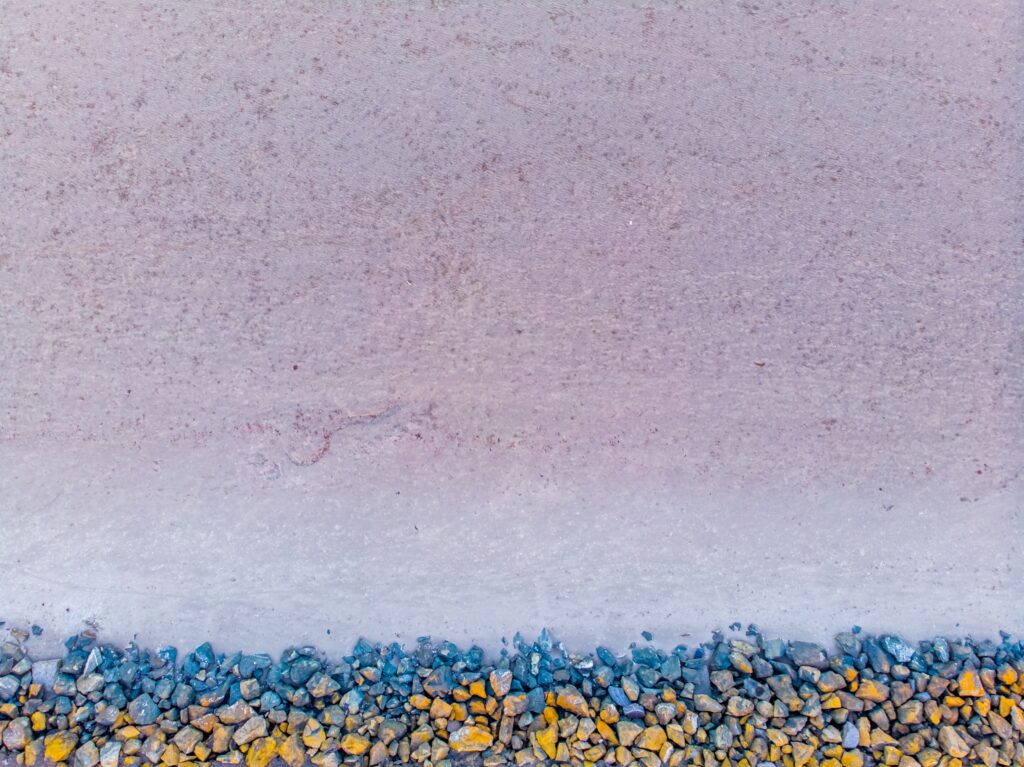 Aerial view of serene beach with yellow blue gray stones on soft textured sand minimalist wallpaper