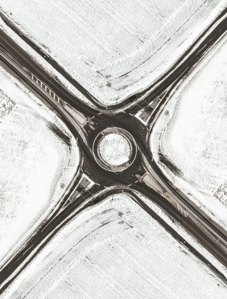Aerial winter landscape with snowy roundabout and roads contrasting dark tarmac minimal wallpaper