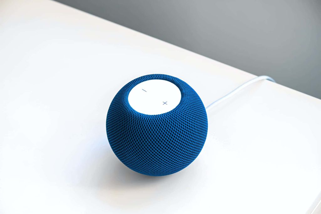 Minimalist blue Apple HomePod mini on white surface showing textured mesh and touch top Wallpaper