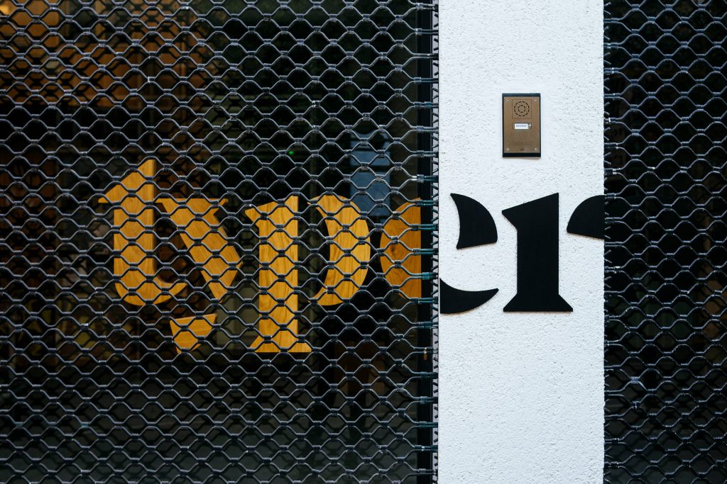 Minimalist photo of typewriter split word with gold type behind black gate and er on pillar Wallpaper