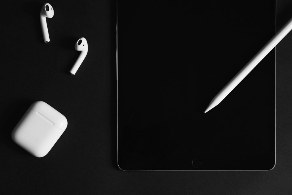 Minimalist black background with Apple AirPods charging case iPad and Apple Pencil wallpaper
