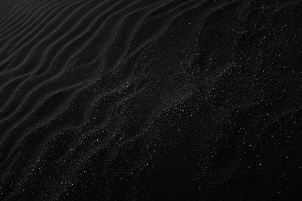 Minimalist black sand dune wallpaper textured ripples dark volcanic sand sleek background