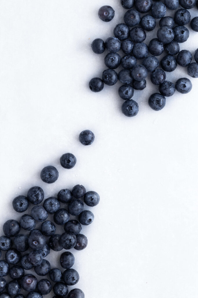 Minimalist wallpaper with fresh blueberries scattered on a clean light background vibrant fruit