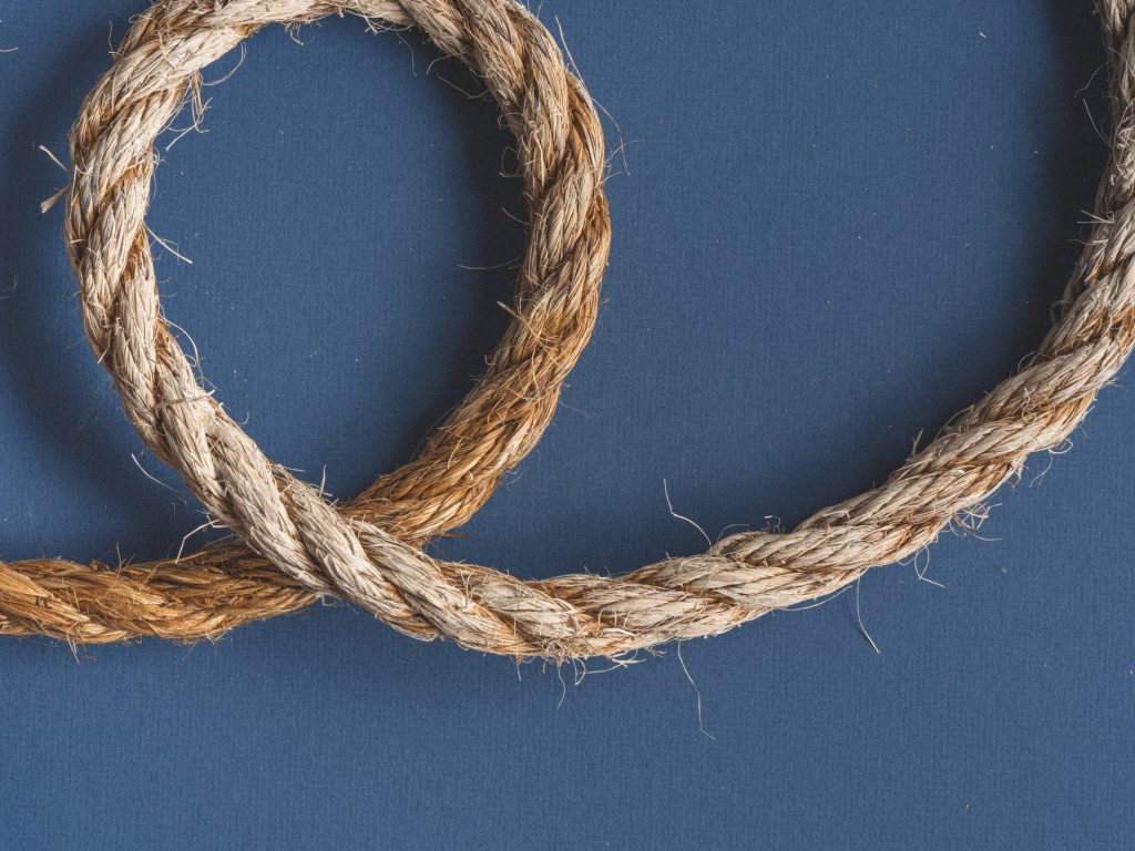 Minimalist wallpaper with brown fibrous rope loop on deep slate blue background modern desktop