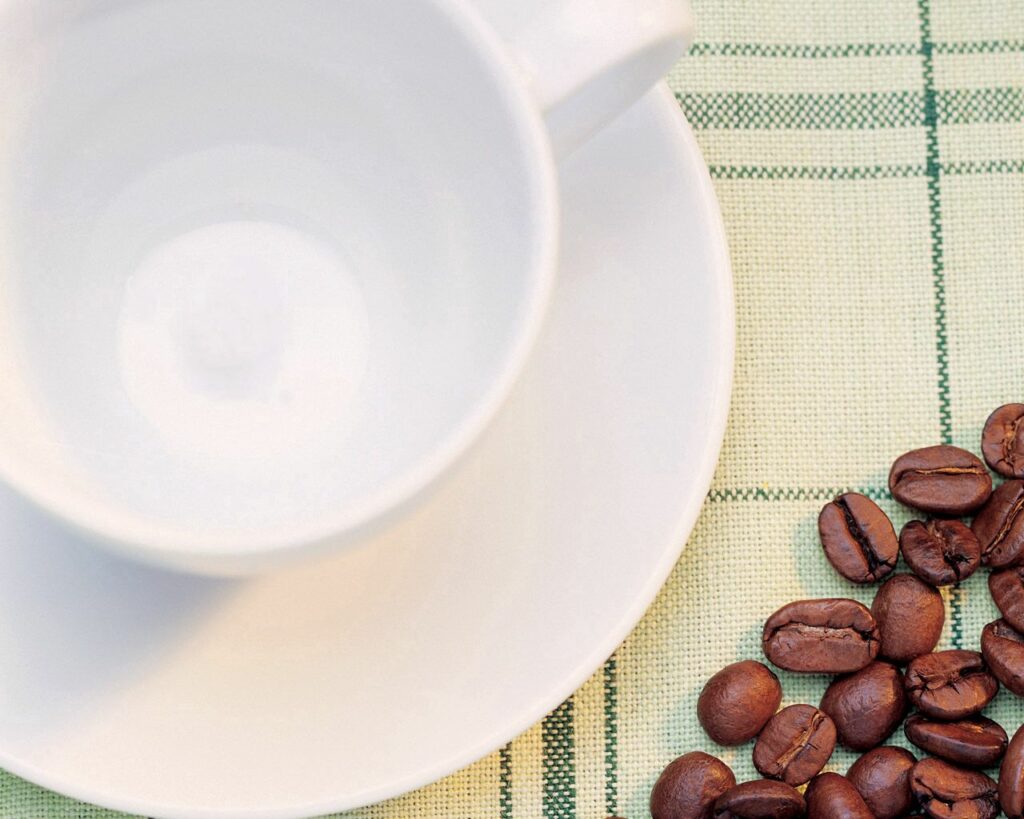 Minimalist Coffee Beans with White Cup on Checkered Fabric Wallpaper