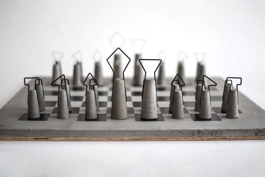 Minimalist concrete chess pieces with black wire outlines on industrial dark inlay board background Wallpaper
