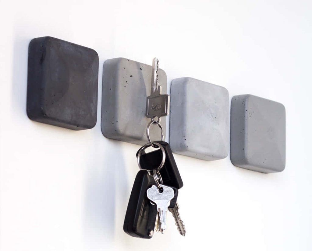 Minimalist modern concrete key holder with four grey blocks and keys on white wall background Wallpaper
