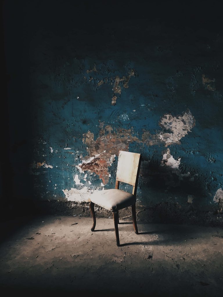 Minimalist cream chair spotlighted against rustic deep blue peeling wall for moody decor background Wallpaper