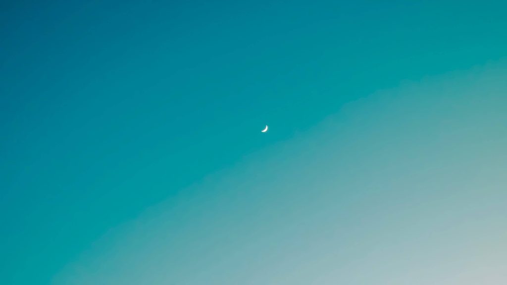 Minimalist crescent moon wallpaper with teal cyan ombre sky for calm digital backgrounds