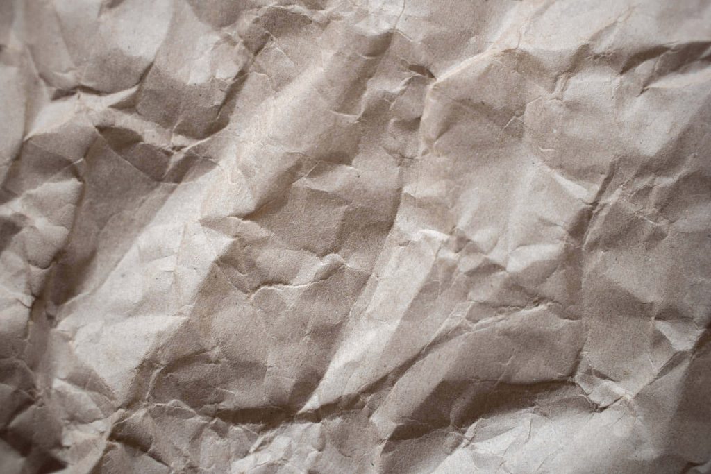 Minimalist crumpled light brown craft paper with textured creases and dynamic rustic lighting wallpaper
