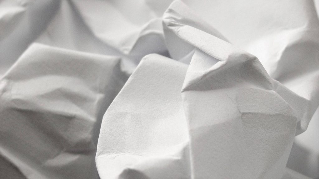 Minimalist crumpled white paper macro wallpaper with soft lighting and deep textured folds background