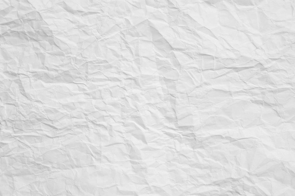 High-resolution crumpled white paper texture wallpaper with deep creases and soft lighting background