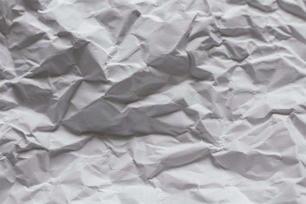 High-resolution crumpled white paper wallpaper with deep creases and soft shadows background