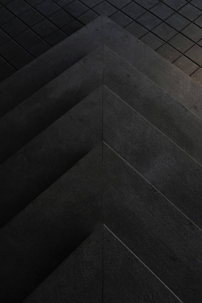 Dark mode mobile wallpaper with symmetrical concrete steps forming a geometric triangle design