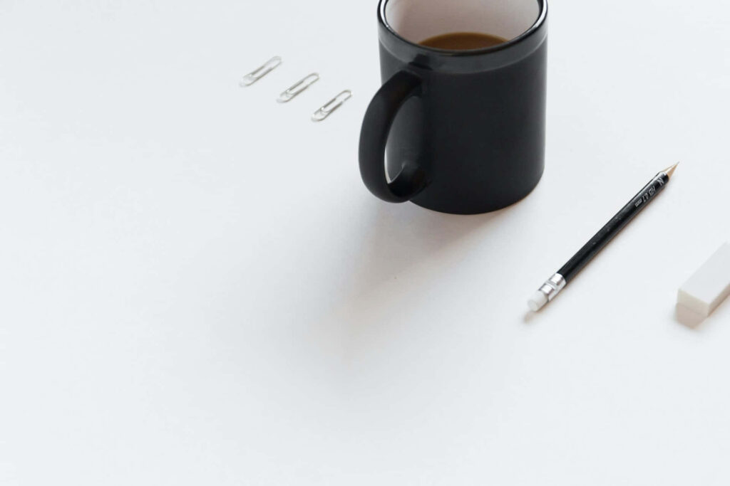 Minimalist Desk Setup: Black Mug, Pencil, Eraser & Paper Clips Wallpaper