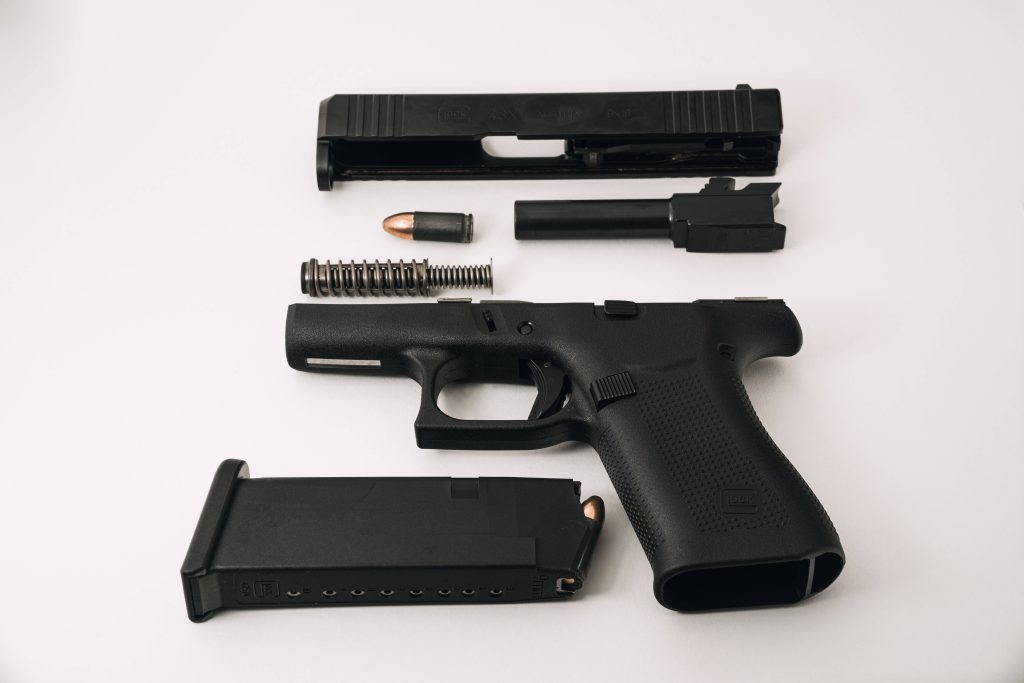 Flat lay of disassembled Glock 43X 9mm handgun parts on white background tactical wallpaper
