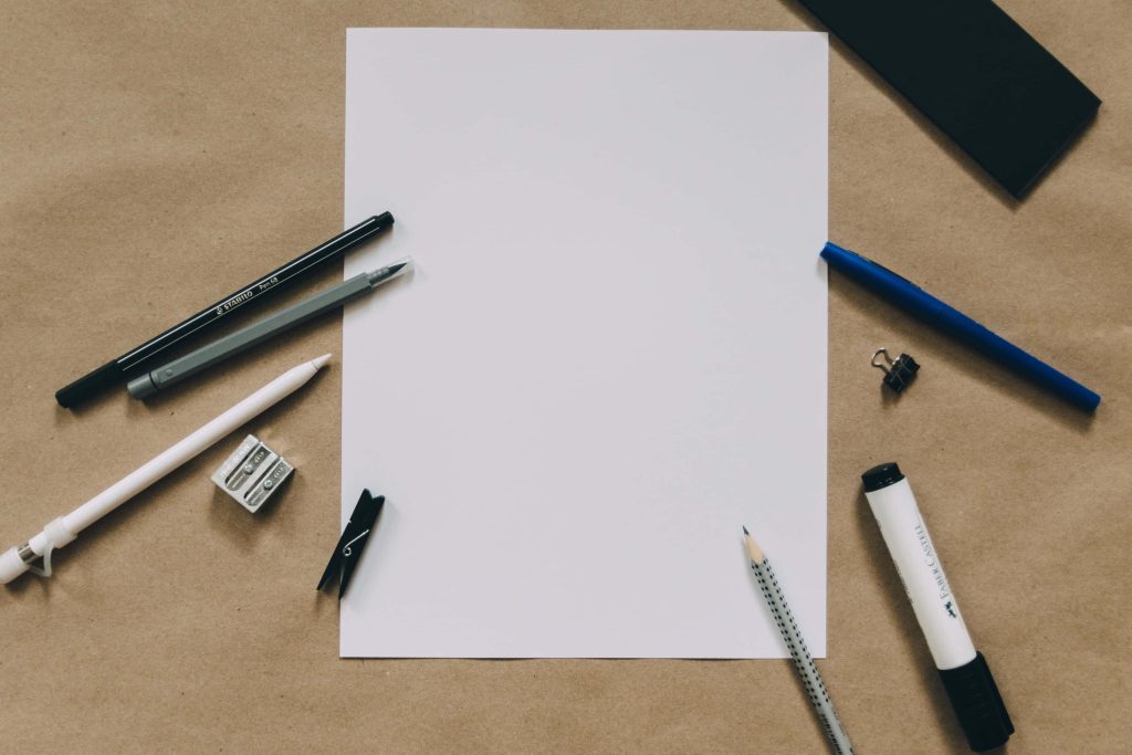 Minimalist flat lay wallpaper with blank white sheet and stationery on rustic tan background