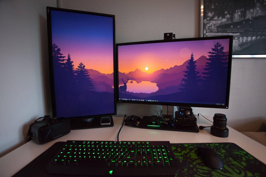 Minimalist gaming workspace with dual sunset monitors Razer keyboard Oculus Rift DK2 on white desk Wallpaper
