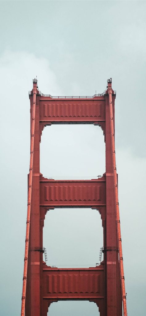 Vertical symmetrical view of Golden Gate Bridge pylon in International Orange against cloudy sky wallpaper