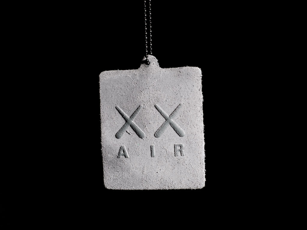 Textured grey KAWS Air Jordan tag with double X and AIR branding on black background wallpaper