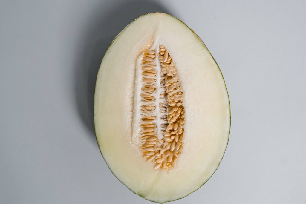 Sliced honeydew melon with seeds on soft gray background minimalist fresh fruit wallpaper