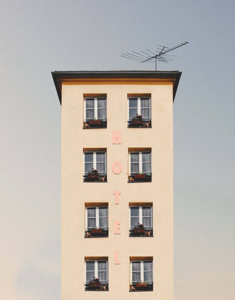 Minimalist hotel facade wallpaper with soft yellow walls and vertical pink hotel lettering
