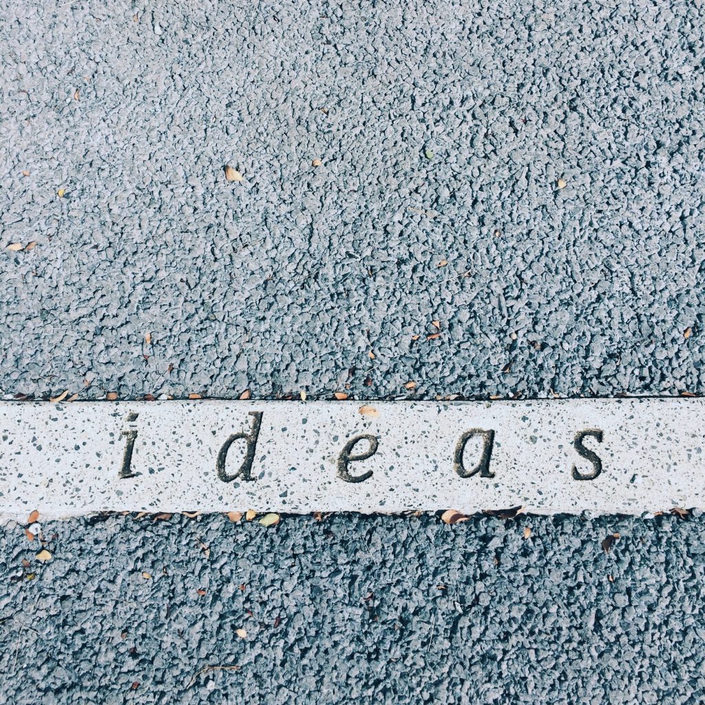 Minimalist wallpaper with the word ideas in serif font on white stripe over textured gray asphalt