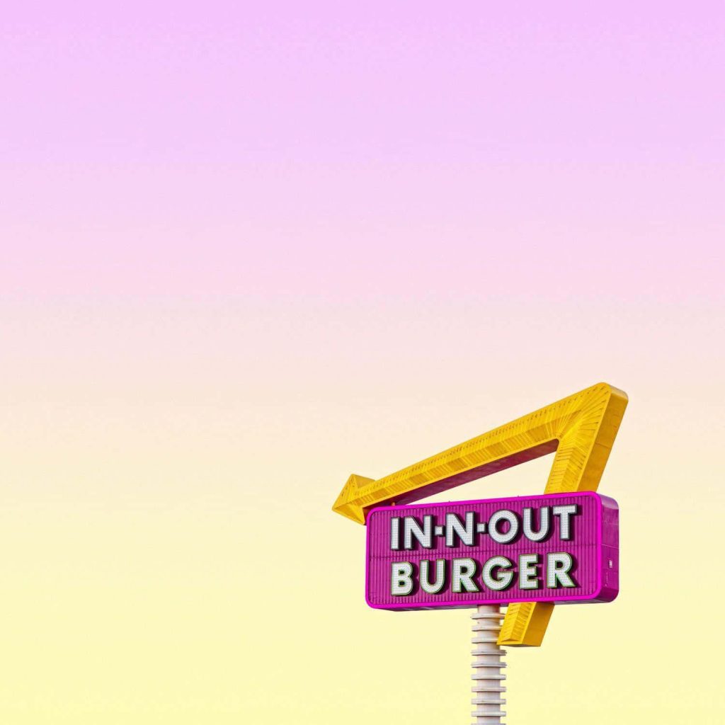 Minimalist In-N-Out Burger wallpaper with yellow arrow magenta sign on pastel gradient sky