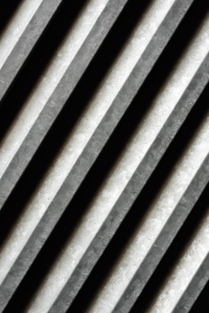 Close-up of industrial corrugated metal with diagonal lines and sharp shadows minimalist wallpaper