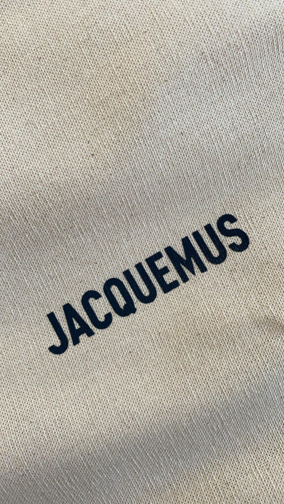 Jacquemus logo in bold black on textured beige fabric minimalist stylish wallpaper background