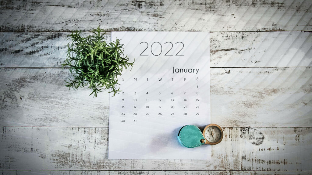 Minimalist January 2022 calendar on rustic white wood table with potted plant and vintage compass Wallpaper