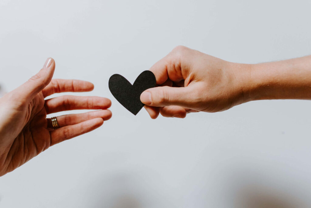 Minimalist Kindness: Hand Offering Black Heart - Wallpaper Background