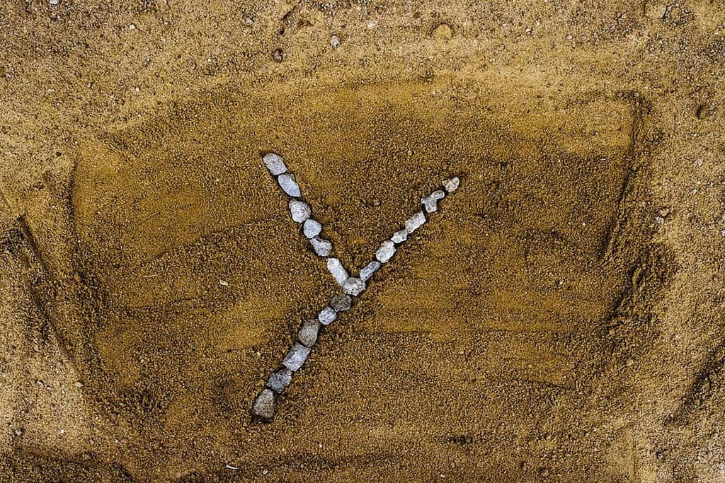 Top-down view of letter Y made from grey rocks on sandy ground minimalist natural wallpaper background