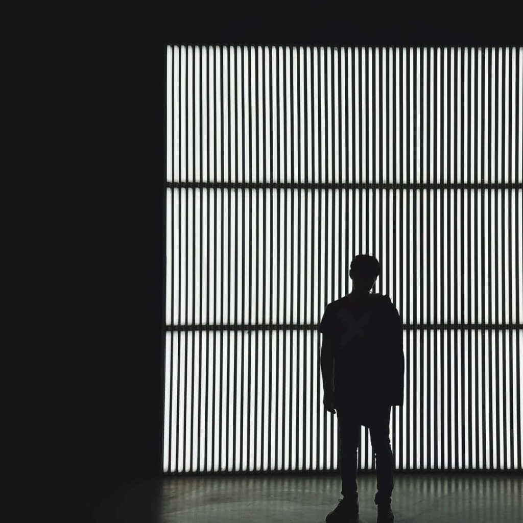 Silhouetted Man Against Striking Illuminated Vertical Stripes Background Wallpaper