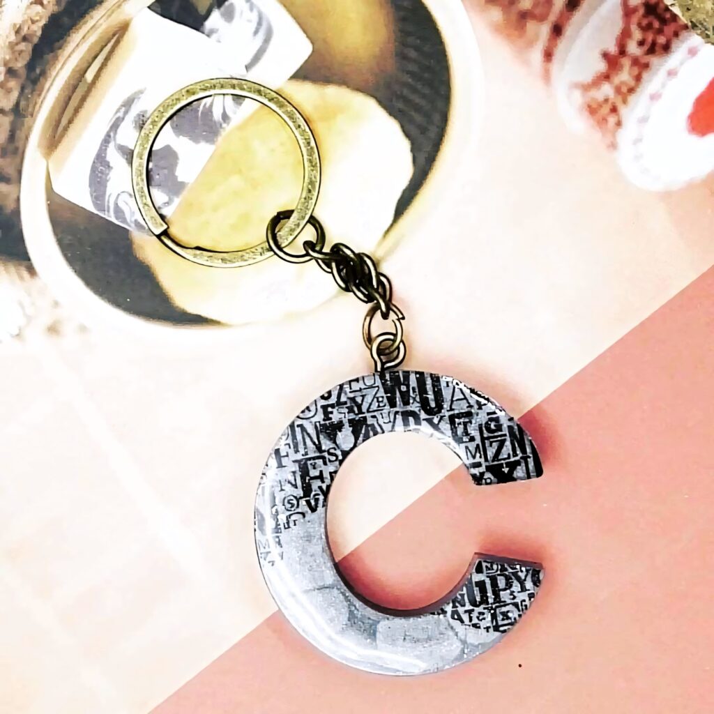 Minimalist Letter C keychain with metallic finish on soft geometric background wallpaper