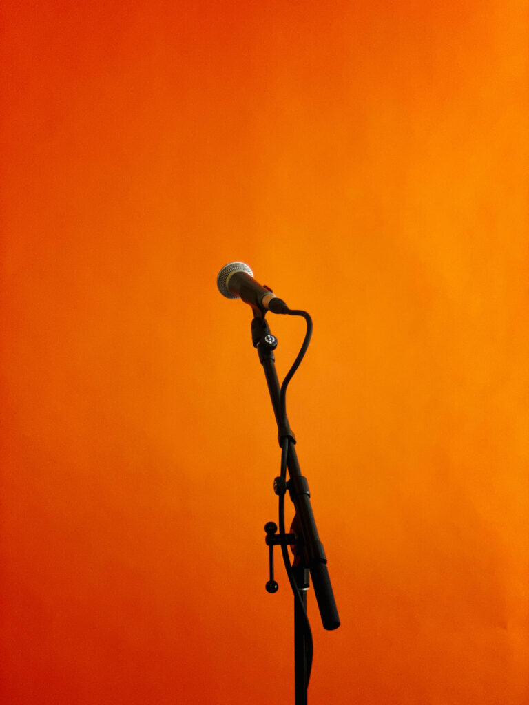 Minimalist Microphone Stand Wallpaper Against Vibrant Orange Backdrop