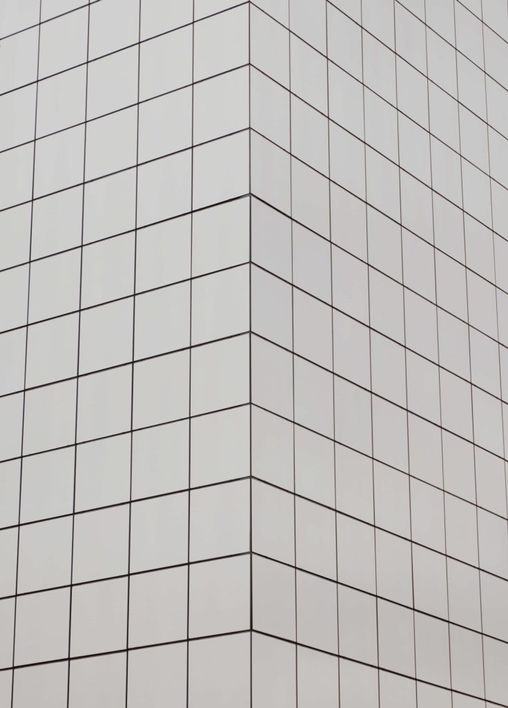 Sharp corner of modern building with light gray square panels and thin dark grid lines Wallpaper