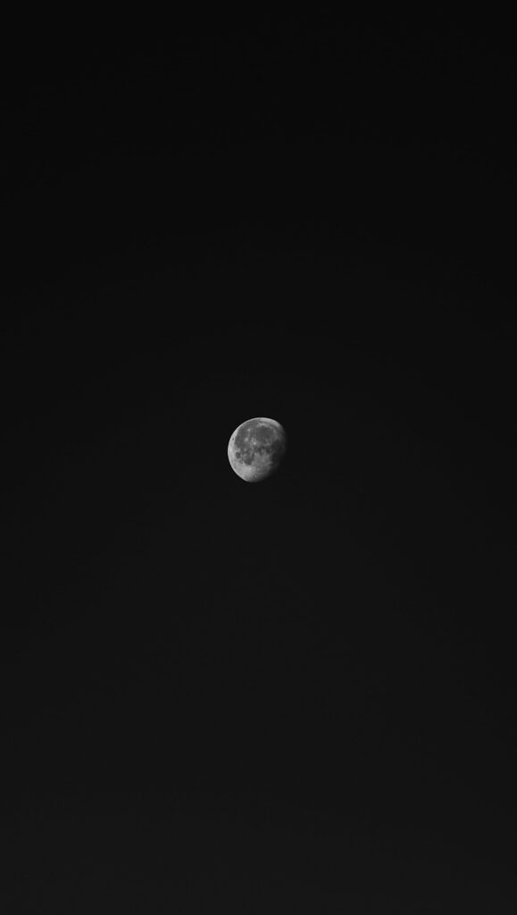 Serenity in Space: A Sleek Black Moon against a Minimalistic Sky - an HD Phone Wallpaper