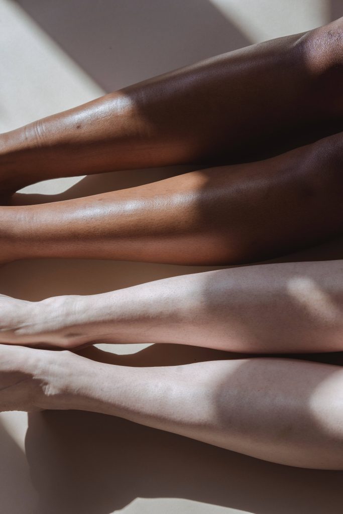 Minimalist photo of diverse legs on tan background with soft natural light and shadows wallpaper