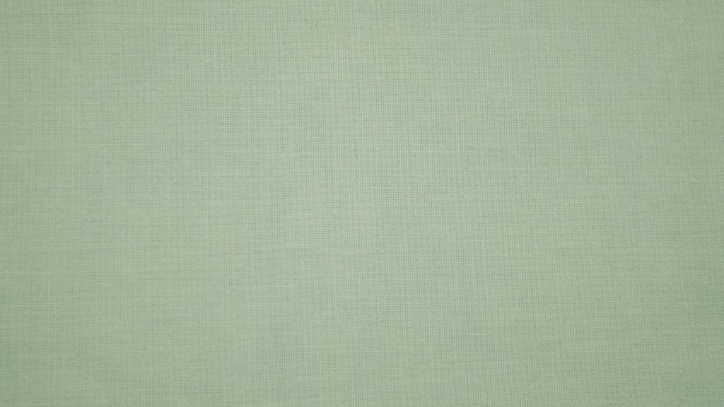 Minimalist pale green textile wallpaper with finely woven fabric texture for workspace background