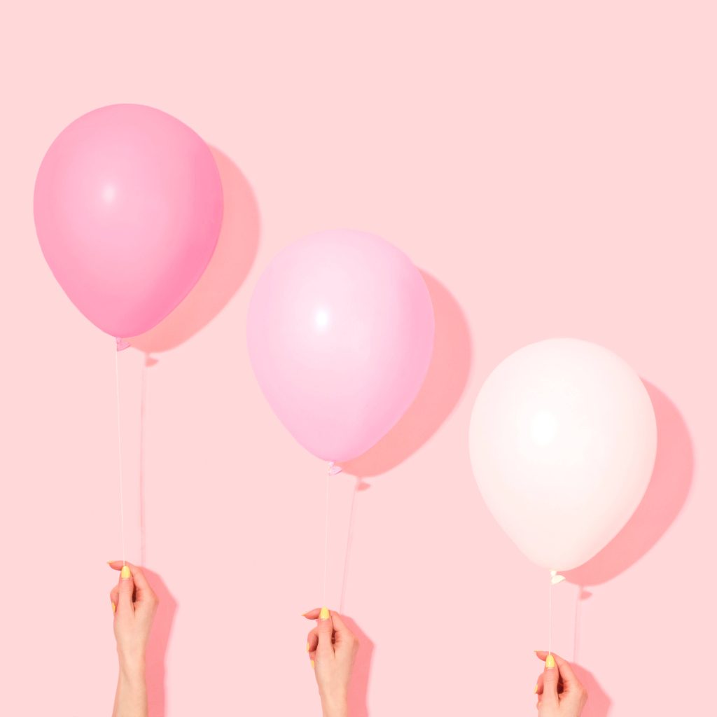 Minimalist wallpaper with three hands holding pastel pink balloons on soft pink background