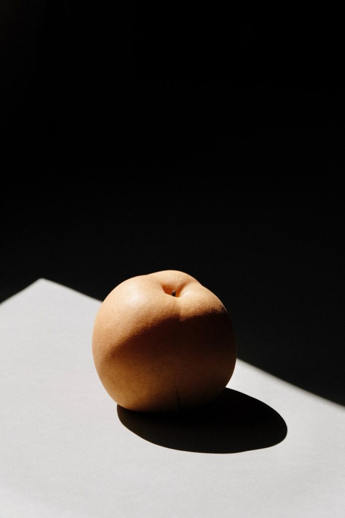 Minimalist Ripe Peach Wallpaper: Soft Shadow on Light Surface