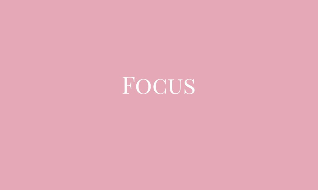 Minimalist pink desktop wallpaper with white serif FOCUS text on soft pastel background