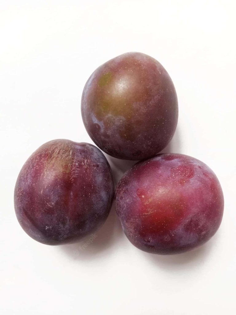Three ripe deep purple plums arranged in a triangular composition on white background wallpaper