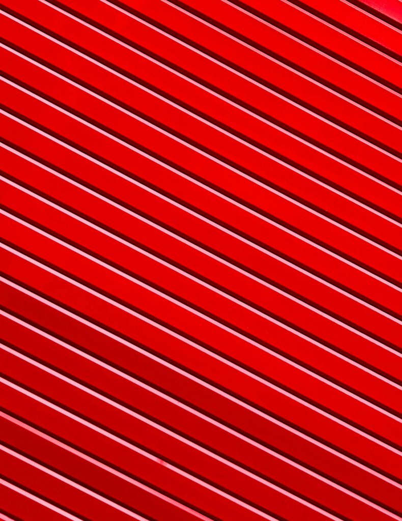 Minimalist abstract wallpaper with vibrant red diagonal lines and geometric corrugated pattern background