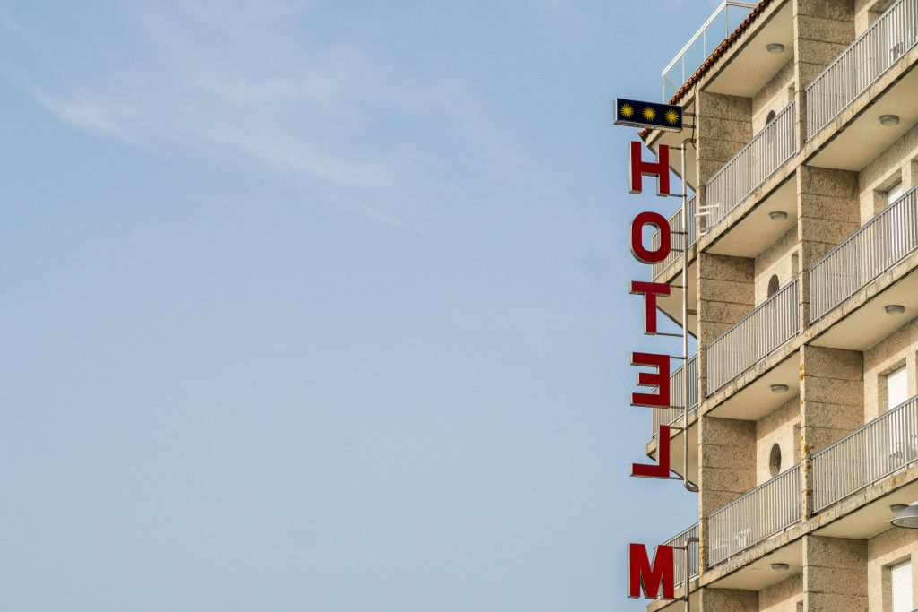 Minimalist architecture with vertical red HOTEL sign on concrete building under blue sky wallpaper